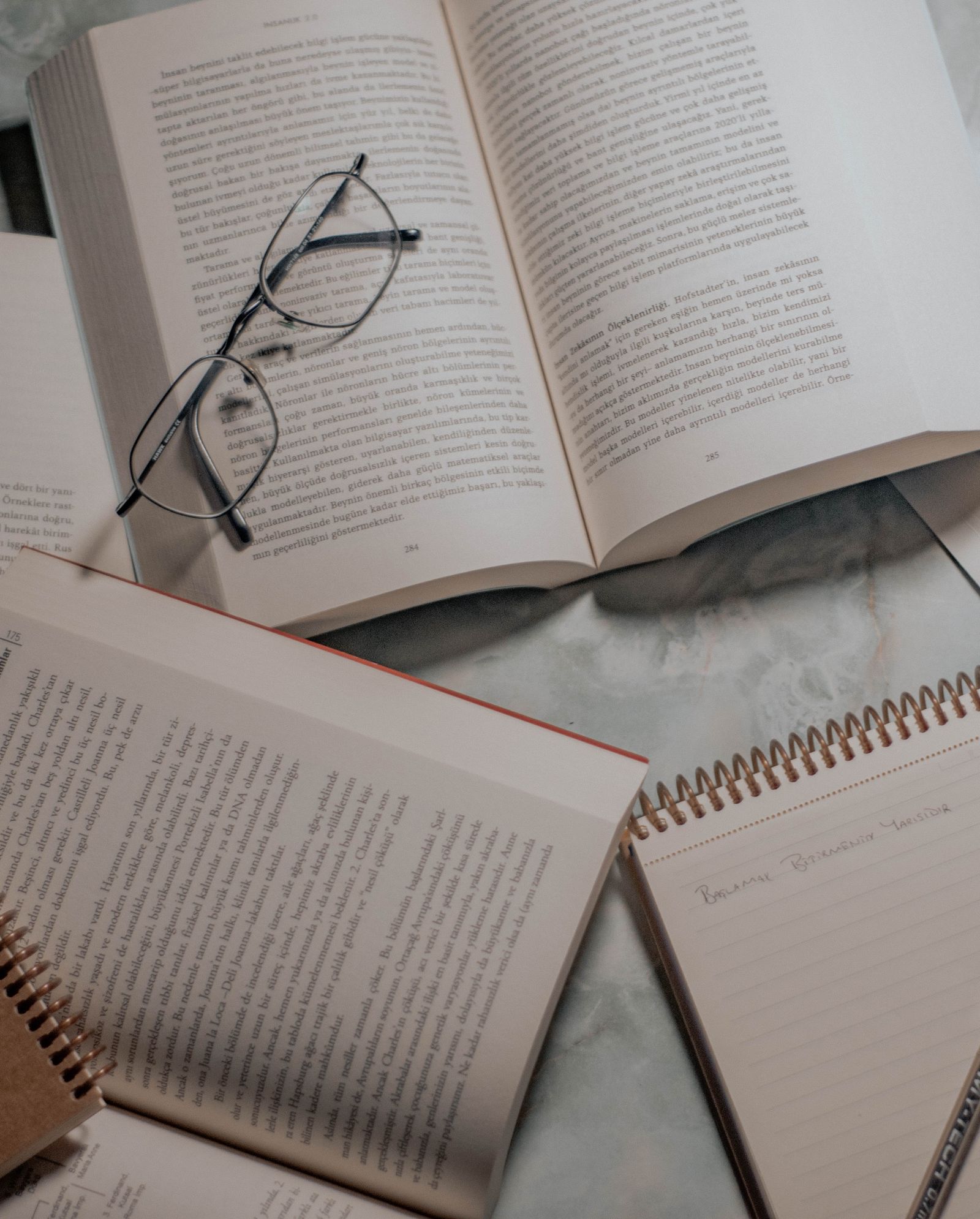 Livres ouverts, lunettes de lecture et carnet à spirale sur une table
